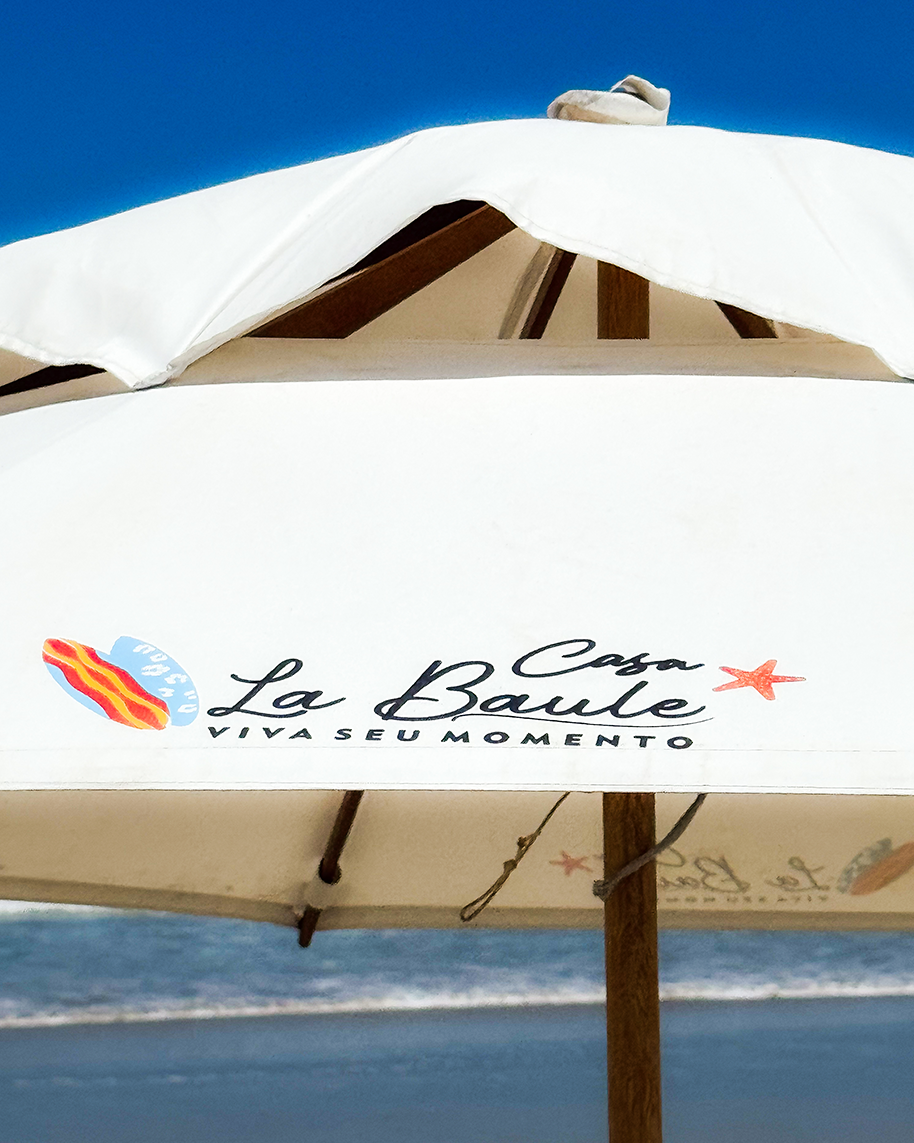 Guarda-sol da Casa La Baule sobre a areia, símbolo de exclusividade