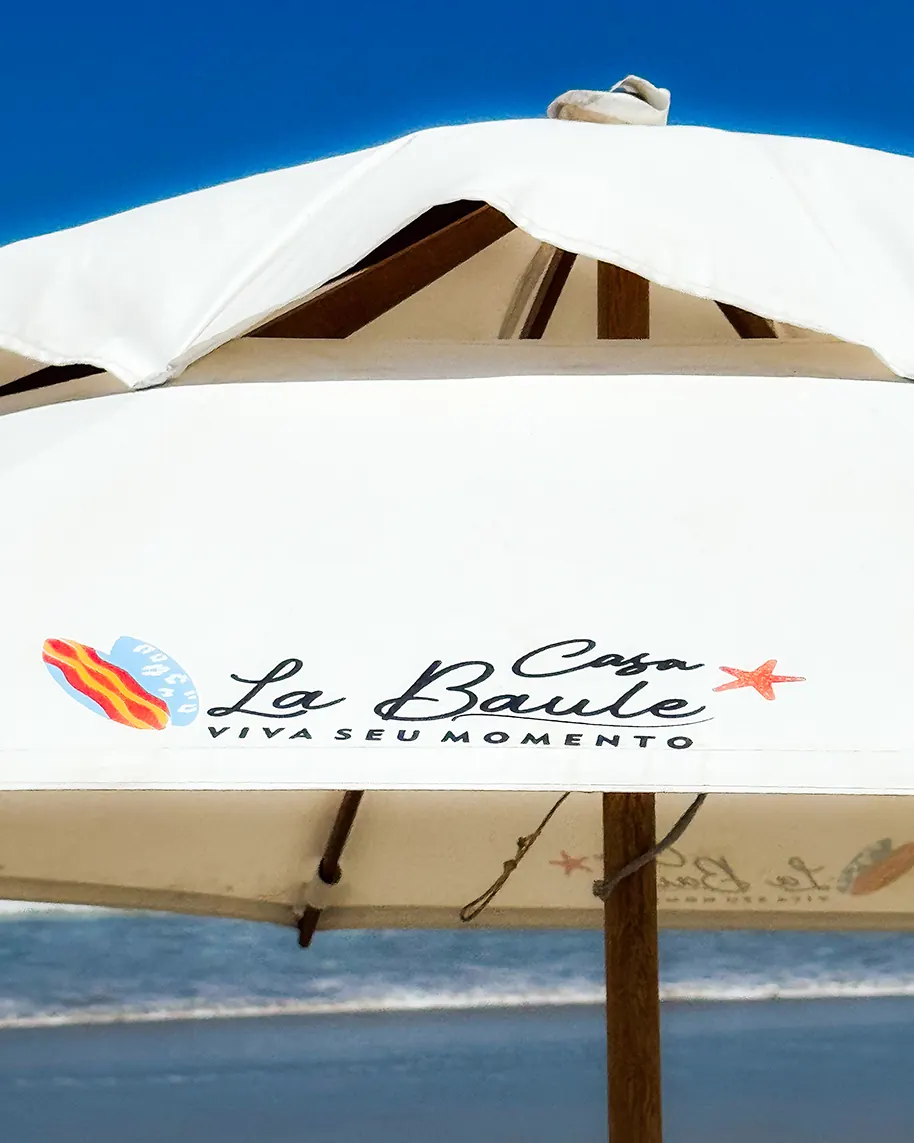 Guarda-sol da Casa La Baule sobre a areia, símbolo de exclusividade